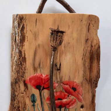 kleines Holzstück mit aufgemalten Mohn und einer abgeblühten Mohnkapsel